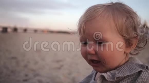 小卷曲的女孩在海滩上吃了无味的沙子吐了又吐视频的预览图