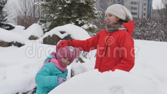 孩子们在冬天玩雪球两个姐妹塑造雪球扔给你的朋友视频的预览图