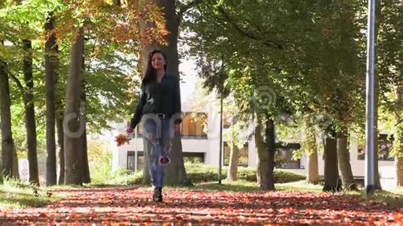美丽的黑发女孩走在小巷的秋天视频的预览图