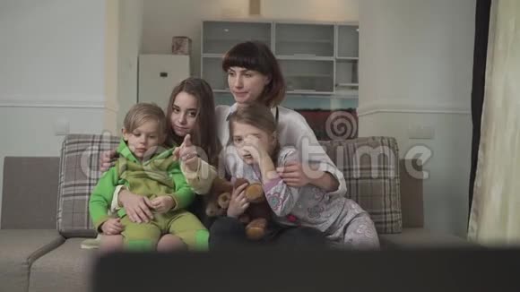 一家人坐在客房的沙发上有感情地看电视年长的姐妹和弟妹花时间视频的预览图