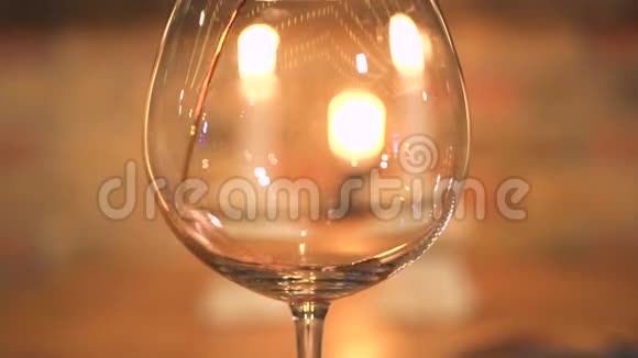 在带有蜡烛背景的晚餐中在空酒杯中倒入红酒红酒从瓶子里倒出来视频的预览图