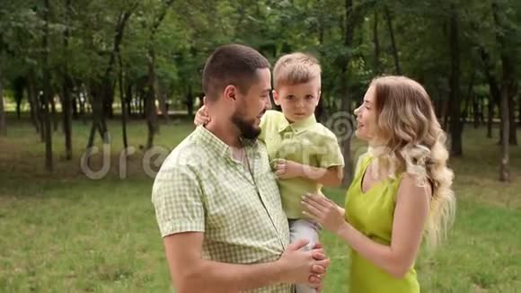 一位年轻的母亲和她的丈夫和儿子在一个夏季公园散步视频的预览图