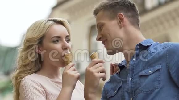 一对年轻夫妇一边吃冰激凌一边笑享受浪漫约会特写镜头视频的预览图
