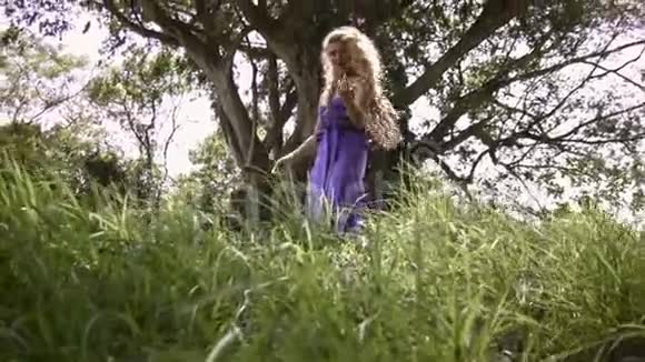 年轻性感女人一头卷发穿着优雅的紫色裙子视频的预览图