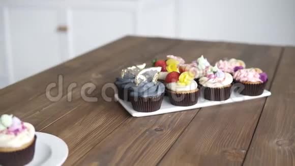 工作室厨房木桌上装饰的糕点的录像不同颜色的纸杯蛋糕摩丝奶油粉红色蓝色视频的预览图
