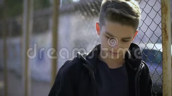 男孩靠在篱笆上穿着帽衫寄宿学校的孤儿禁闭视频的预览图