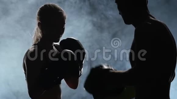 教练和拳击赛上的女孩从后面的光剪影烟雾背景慢动作视频的预览图