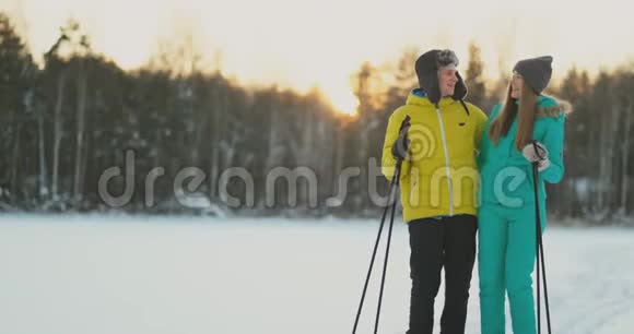 在冬天的森林里在日落时分情侣们滑雪环顾四周看看大自然的美丽和缓慢的景点视频的预览图