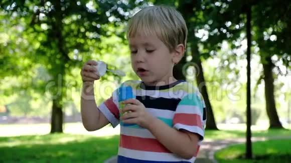 可爱的男孩在户外吹肥皂泡夏天的背景童年观念视频的预览图