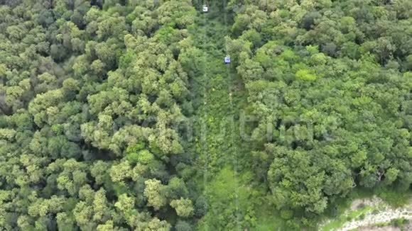 在绿色森林背景下在山上移动的空中观景缆车舱视频的预览图