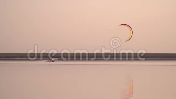 一个人在平静的湖面上滑行日落时控制着一只训练风筝视频的预览图