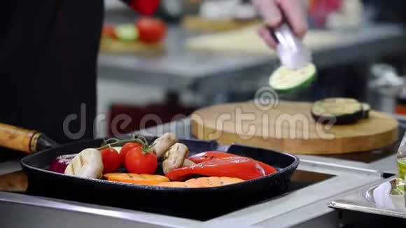 在厨房工作的厨师把锅里的炒菜放在木桌上视频的预览图