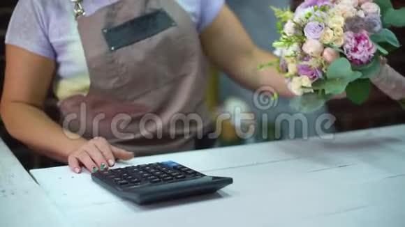 在一家花店的特写中女花店用计算器计算花束的成本视频的预览图