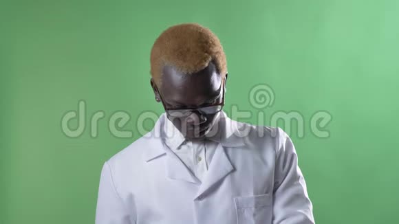 穿着白大褂的年轻的非洲金发医生摸着眼镜看着摄像机被隔离在色度键背景上视频的预览图