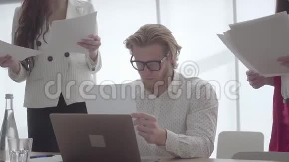疲惫的男人坐在一间舒适的办公室里桌上放着上网本检查女同事给的文件视频的预览图