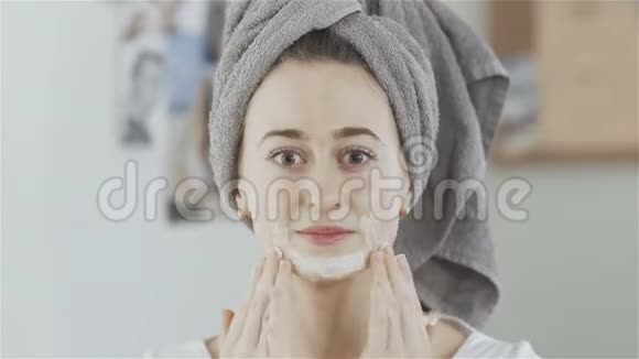 头上戴毛巾的女人戴上化妆面具看着镜头视频的预览图