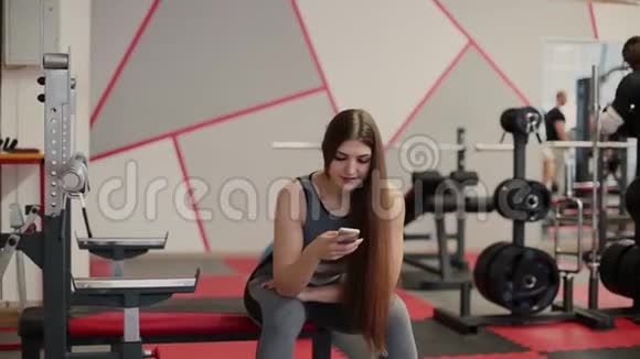 健康女性使用健身可穿戴技术在健身房锻炼后在智能手机上检查身体统计数据视频的预览图