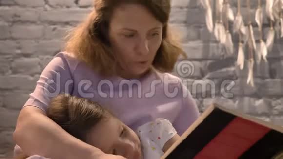 妈妈给小女儿读书孩子躺在父母的腿上听尾巴家庭观念在家里在室内视频的预览图