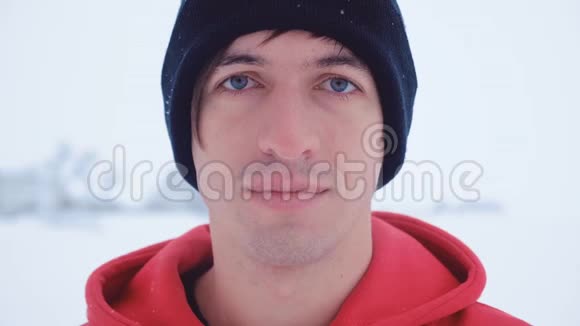这位迷人的年轻人的特写镜头在寒冷的冬天在户外看着相机微笑视频的预览图