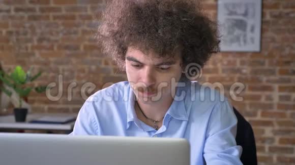 讨厌的书呆子办公室工作人员咳嗽用笔记本电脑工作坐在有砖墙背景的现代办公室里视频的预览图