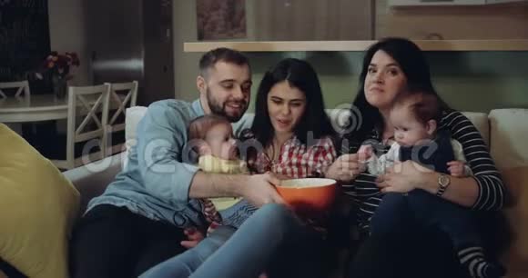 快乐的大家庭和他们的孩子一起看电视吃爆米花红色史诗视频的预览图