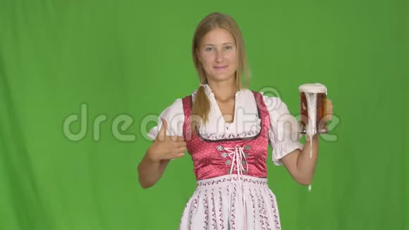 穿着巴伐利亚民族服装的女孩在绿色背景下喝啤酒视频的预览图