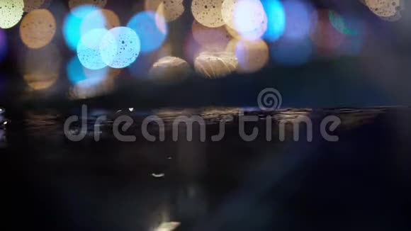 慢动作特写雨滴落在水坑上城市人行道上有灯光反射视频的预览图