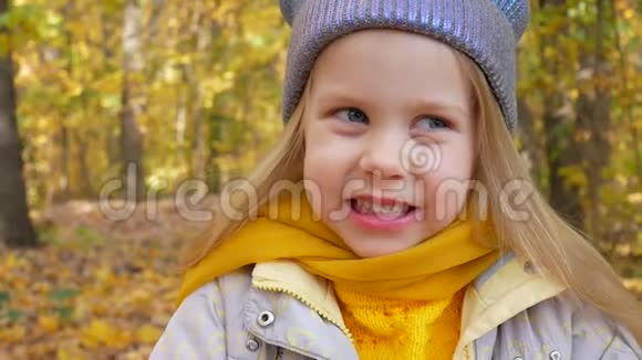 秋天黄色落叶背景下森林或公园里的小可爱女孩视频的预览图