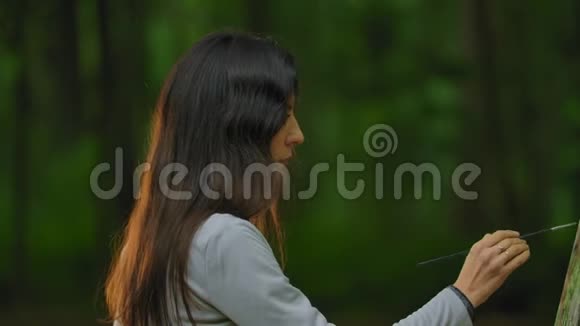 美丽的女人在森林里画着大自然的风景视频的预览图