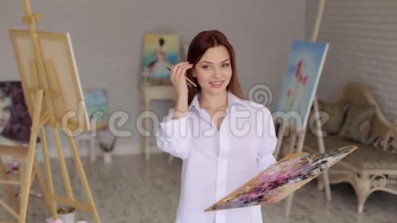 一个笑女孩画家的肖像在一个灯光工作室与调色板的颜色视频的预览图