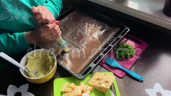 一个女人在烤盘上形成土豆圈借助糕点包奶酪洋葱片和炸蘑菇都在上面视频的预览图