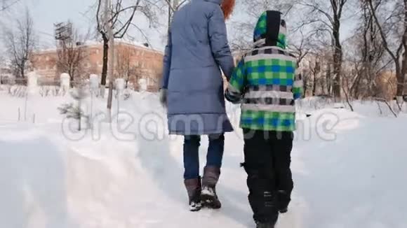 妈妈和儿子在冬天的城市公园散步后景视频的预览图