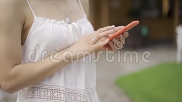 穿白衣服的女人用手机手里拿着智能手机的女人关门视频的预览图