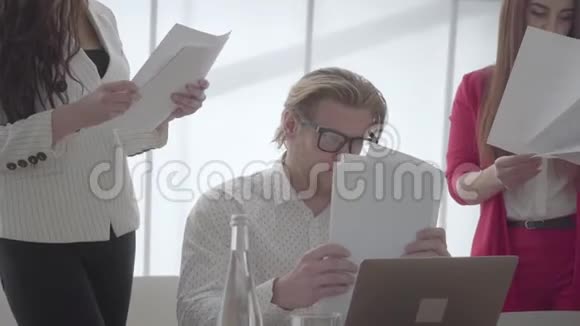 肖像疲惫的男人坐在舒适的办公室里桌上放着上网本检查女同事的文件视频的预览图