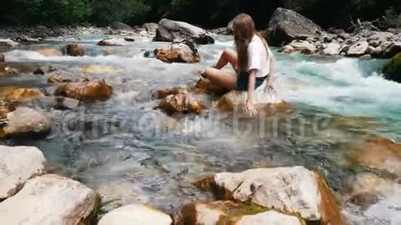 女孩坐在石山河上手牵着她们穿过水享受着新鲜的生活视频的预览图