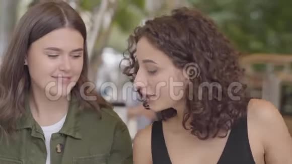 两个女孩坐在户外咖啡馆的肖像闲的少女们在一起友好的关系视频的预览图