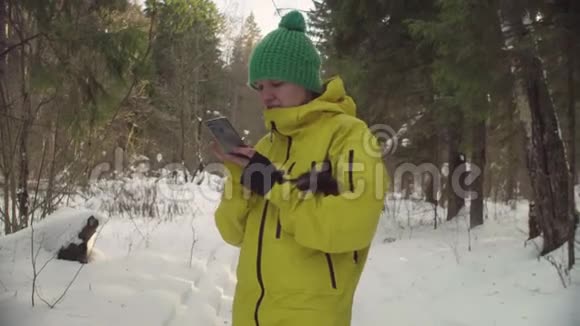 冬天森林里的女人用智能手机打字视频的预览图