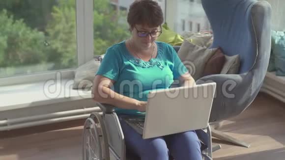 坐轮椅的女商人在家里用笔记本电脑工作慢节奏视频的预览图