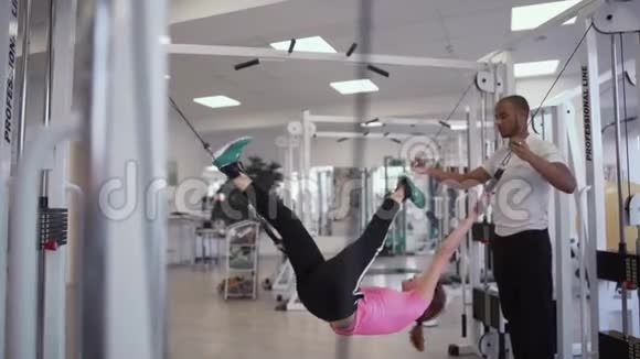教练帮助女性伸展她的身体挂在健身房的绳子上在健身房健康的生活方式视频的预览图