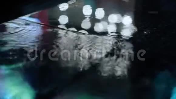 慢动作特写雨滴落在水坑上城市人行道上有灯光反射视频的预览图