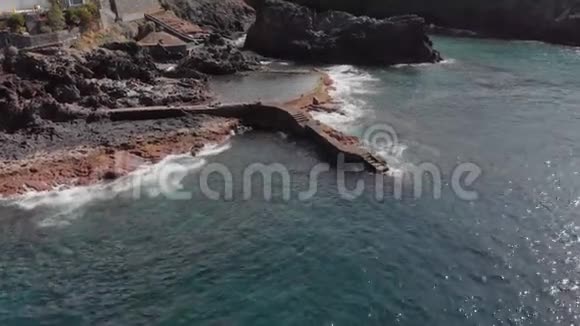 空中射击阳光明媚的一天在海洋和岩石火山海岸上空盘旋蓝色的海岸视频的预览图