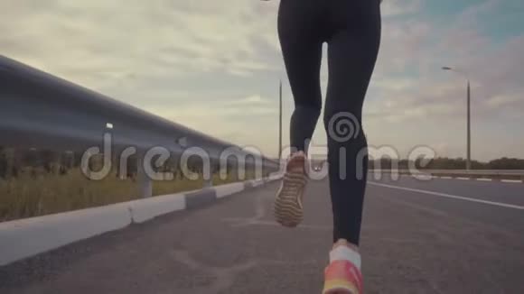 夕阳下的田径课一个穿着白色t恤留着长发的运动女孩在一条空跑道上奔跑视频的预览图