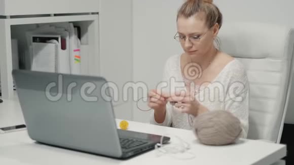 办公室里的成熟女人在编织一个女人在办公室打毛衣休息时坐在办公室里视频的预览图