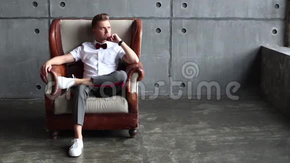 一个严肃的年轻人坐在一张老式的皮椅上视频的预览图