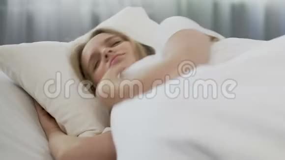 漂亮的女孩躺在舒适的床单上懒得起床上课迟到视频的预览图
