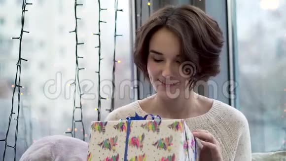 考虑新年礼物的女人美丽的年轻女子穿着毛衣带着微笑和好奇心正在考虑圣诞礼物视频的预览图