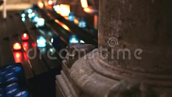 从一个古老的石柱后面可以看到天主教堂内部的几支蜡烛视频的预览图