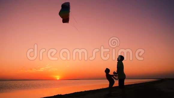 日落时两个孩子一起放彩虹风筝视频的预览图