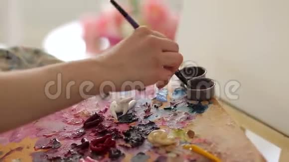 一位女艺术家的特写镜头洗了一把刷子在水里画画视频的预览图