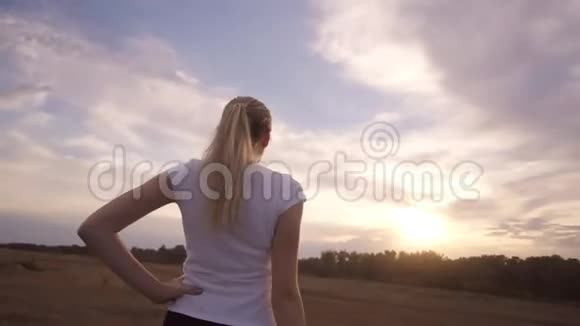 积极的生活方式和保健一个穿着白色t恤长发的运动女孩站在夕阳下视频的预览图
